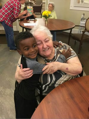 A child hugging a smiling resident in a common area