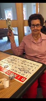 A resident playing bingo, smiling while holding cash.