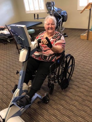 Resident using adaptive exercise equipment in a facility gym