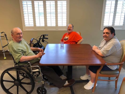Three male residents sitting at a table in a common area