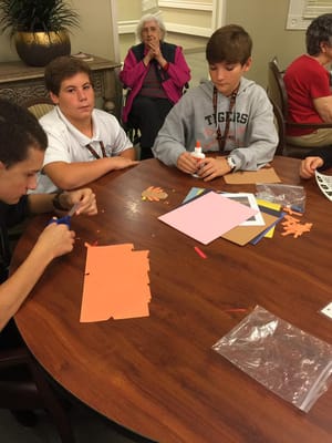 Residents and youth engaged in a craft activity at a table