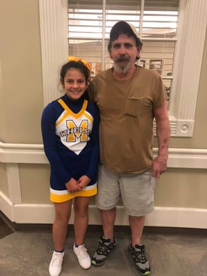 A young cheerleader with an older gentleman indoors