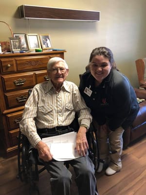 A resident and staff member in a cozy room.
