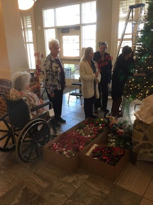 Residents decorating a Christmas tree in a common area