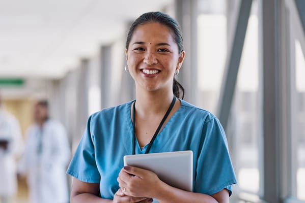 Smiling healthcare worker in scrubs in a hallway