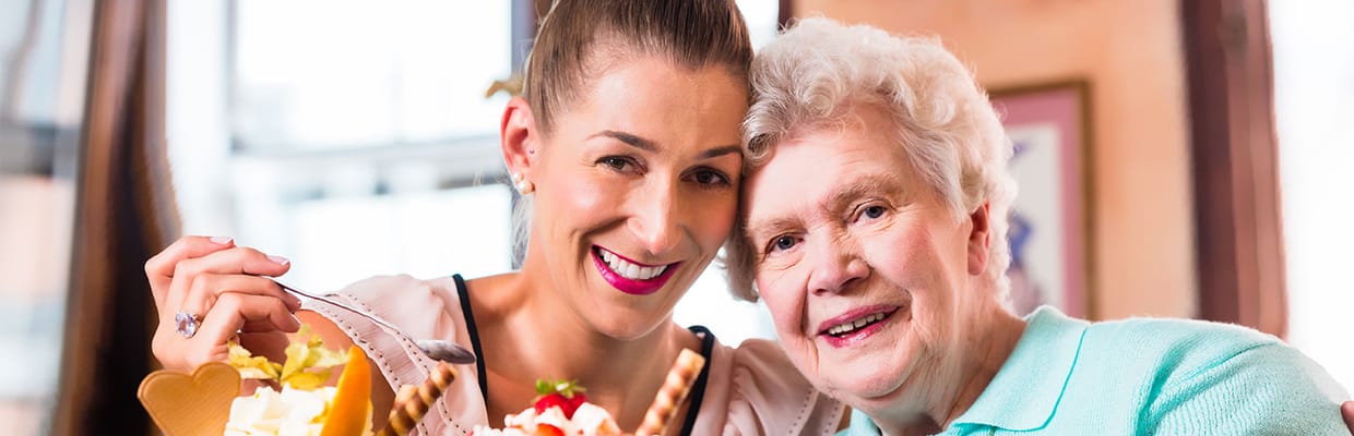 Staff member and resident smiling together with dessert