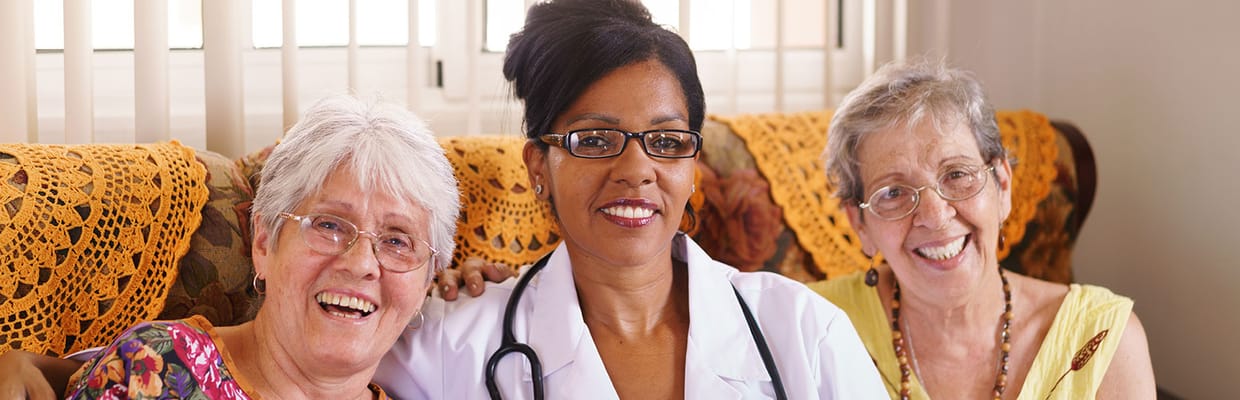 A caregiver with two smiling residents in a cozy room