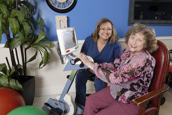 Staff assisting a resident with exercise equipment