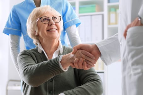 A resident and caregiver shaking hands in an activity room
