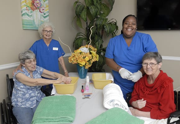 Residents enjoying a hand spa activity with staff assistance