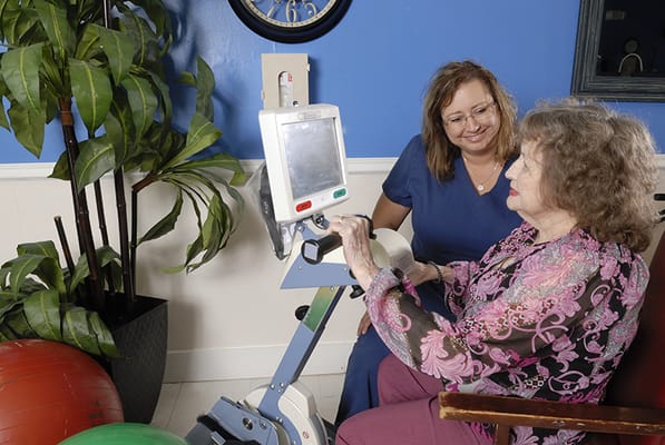 Therapist assisting a resident with equipment in an activity room