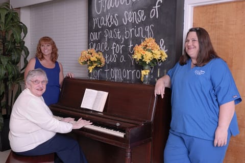 Residents and staff enjoying music at a piano