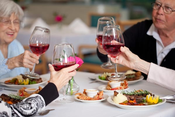 Residents toasting with drinks at a dining table