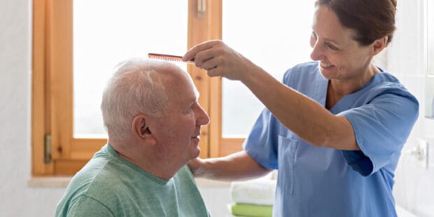 A caregiver using a comb on a resident's hair