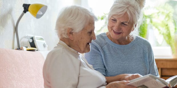 Caretaker reading with senior resident in cozy setting