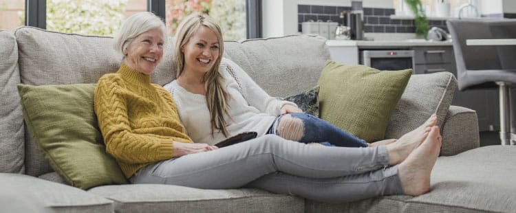 Two women smiling together on a cozy couch
