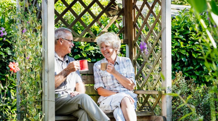 Two residents enjoying tea in a garden gazebo