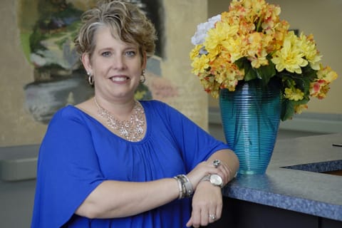 Staff member posing near colorful flowers at reception