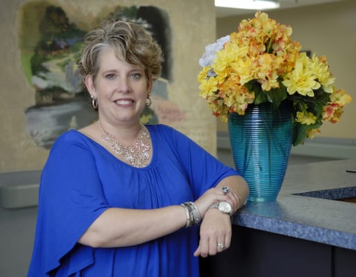 Staff member posing with floral arrangement in the facility.