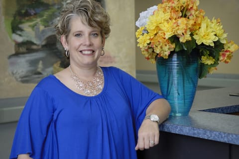 Staff member smiling beside a flower arrangement in the lobby