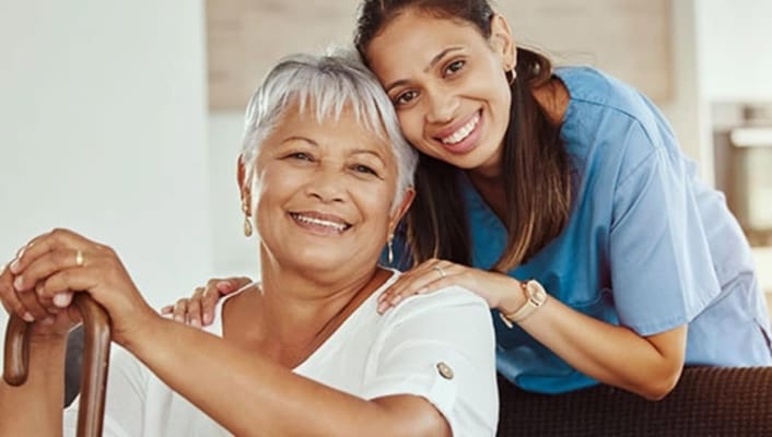 Resident and caregiver smiling together in a facility