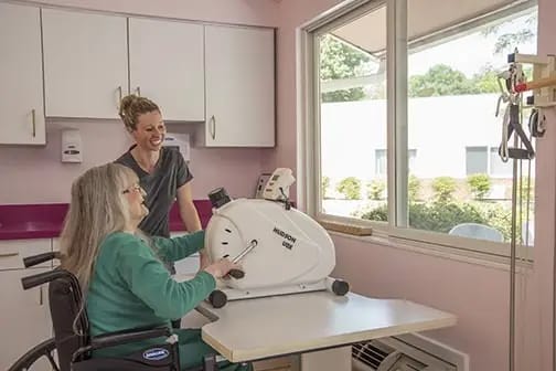 Resident using therapy equipment with staff supervision