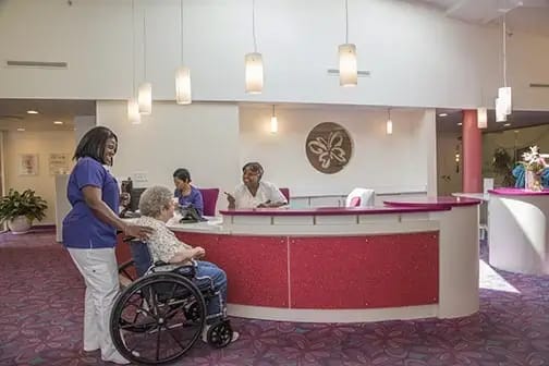 Staff assisting a resident in a brightly lit lobby