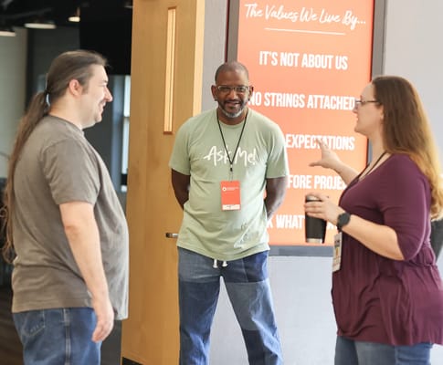 Three people engaging in conversation in a facility interior