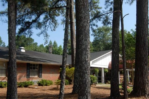Exterior view of Pine Knoll Nursing & Rehab Center surrounded by trees