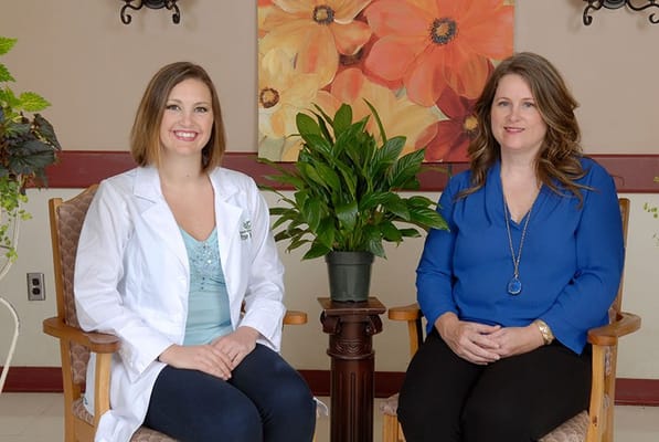 Two staff members posing in a comfortable seating area