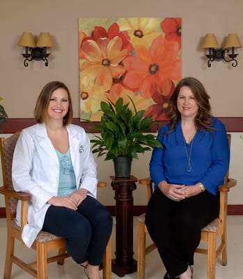 Two staff members sitting in a common area with floral decor