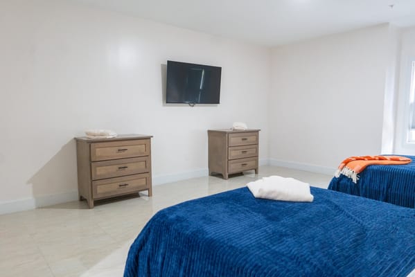 A shared resident room with two beds and a TV