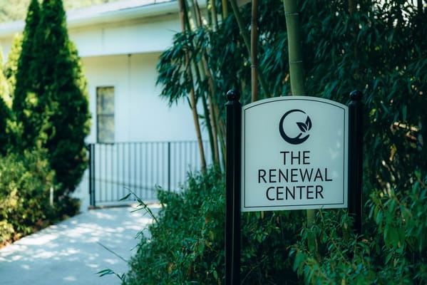 Sign for The Renewal Center surrounded by greenery
