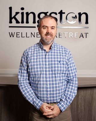 Staff member posing in front of the facility logo