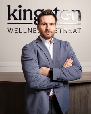 Staff member posing in front of the facility's logo