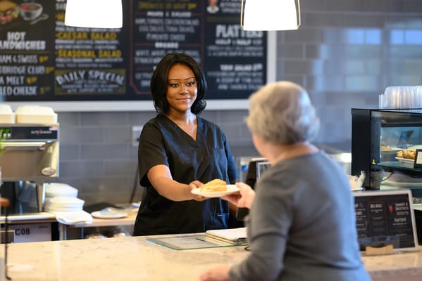 A staff member serving food to a resident in the dining area