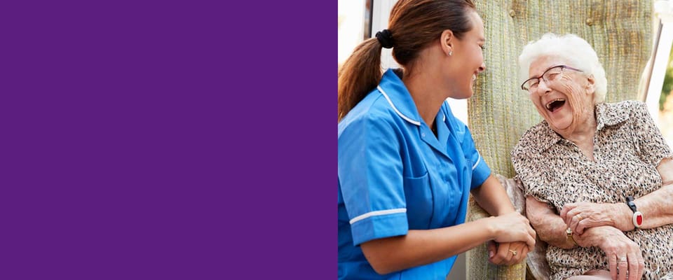 A caregiver laughing and talking with an elderly resident