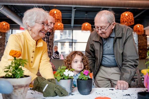 Residents and a child planting flowers together indoors