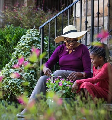An elderly woman gardening with a child in a vibrant outdoor space