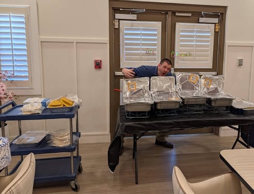 Staff member with food trays in a dining area