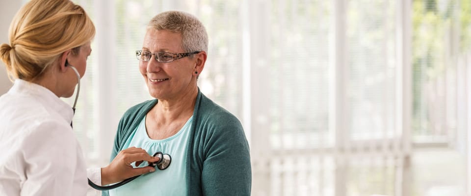 Nurse using a stethoscope on a smiling resident