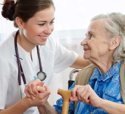 Nurse assisting an elderly woman in a facility