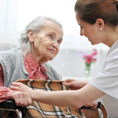 Caregiver attending to an elderly resident in a cozy room