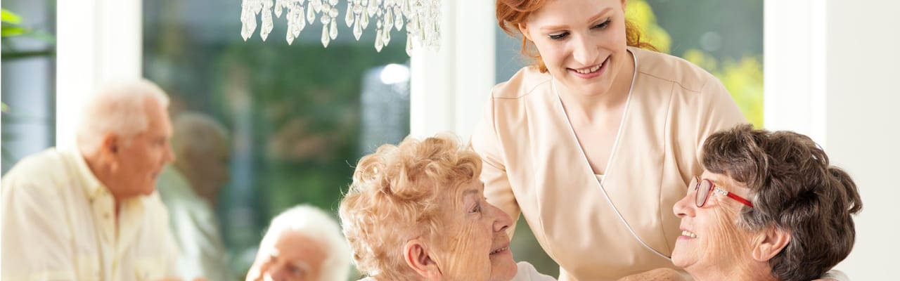 Caregiver interacting with residents in a bright interior space