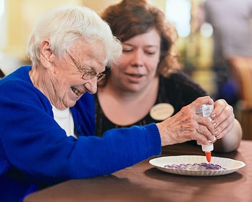 A resident enjoying an activity with staff assistance