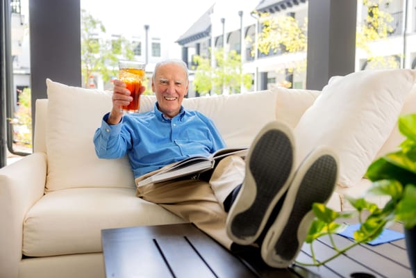 Senior resident enjoying a drink in a relaxed lounge area