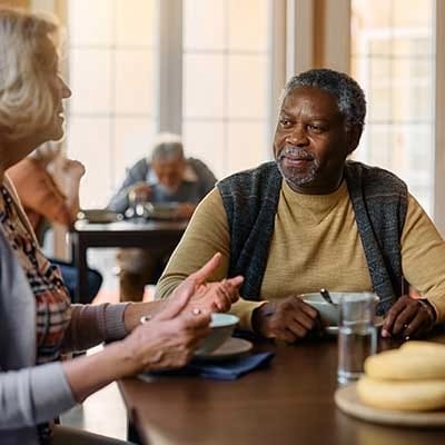Residents enjoying a meal and conversation in the dining room