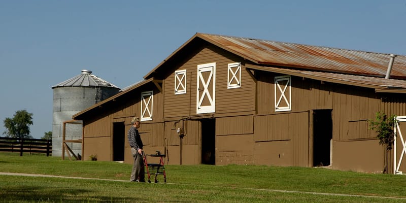 A person using a walker near a barn building