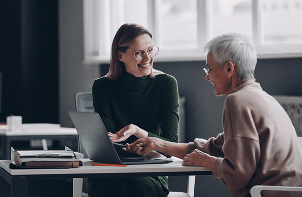 A caregiver and a resident engaged in conversation at a table.