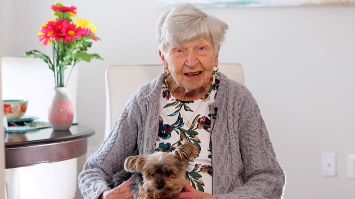 Resident holding a dog in a cozy living area